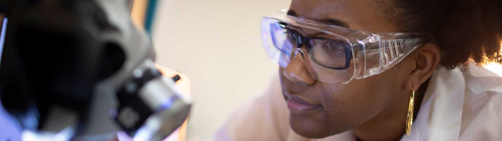 Femme regarde dans un microscope